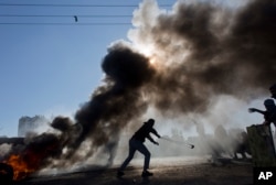 FILE - Palestinian protesters burn tires and clash with Israeli troops following protests against U.S. President Donald Trump's decision to recognize Jerusalem as the capital of Israel, in the West Bank city of Ramallah, Dec. 8, 2017.