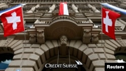FILE - National flags of Switzerland fly over the entrance of the headquarters of Swiss bank Credit Suisse in Zurich July 31, 2014.