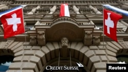 FILE - National flags of Switzerland fly over the entrance of the headquarters of Swiss bank Credit Suisse in Zurich July 31, 2014.