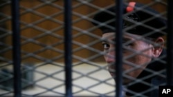 FILE - An Egyptian policeman guards the courtroom defendant's cage during a hearing in a court in Cairo, Egypt.