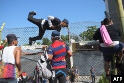 Salvadorean migrants climb and jump over a fence to get to the Guatemala-Mexico international border bridge in Ciudad Tecun Uman, Guatemala, on Nov. 2, 2018.