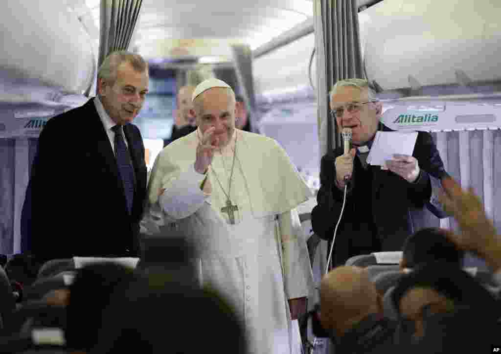 Pope Francis waves to journalists during a press conference aboard the flight towards Ankara, Friday, Nov. 28, 2014.