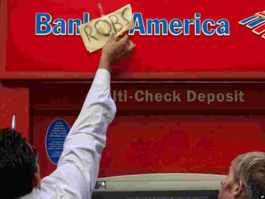 A bank employee peals off a sign left by demonstrators on a bank teller, as part of the Occupy Wall Street movement protests, Thursday, Oct. 6, 2011. Nearly a dozen people were arrested for trespassing Thursday during a sit-in at a Bank of America, ending