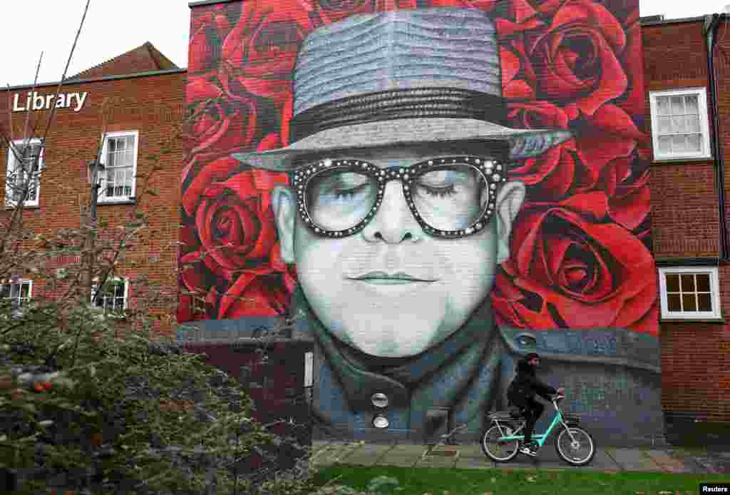 A man cycles past a mural of Elton John in Watford in Hertfordshire, Britain.