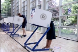 Perwakilan AS. Alexandria Ocasio-Cortez dan rekannya, Riley Roberts, memberikan suara dalam pemilihan awal Kongres Partai Demokrat di borough Bronx, New York City, 20 Juni 2020. (Foto: dok).