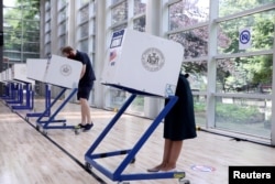 Perwakilan AS. Alexandria Ocasio-Cortez dan rekannya, Riley Roberts, memberikan suara dalam pemilihan awal Kongres Partai Demokrat di borough Bronx, New York City, 20 Juni 2020. (Foto: dok).