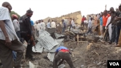 A day after a double bombing in northern Nigeria killed dozens of people, men search the rubble for bodies in Maidguri, March 2, 2014. (Abdulkareem Haruna/VOA)