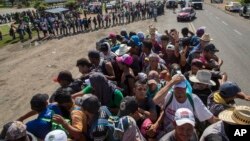 Migrants travel on a truck as others in the back wait in a line for a ride on the road that connects Tapanatepec with Niltepec, Mexico, as a caravan of Central Americans continues its slow march toward the U.S. border, Oct. 29, 2018.