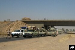 FILE - Iraqi security forces in uniforms and plainclothes head to Baghdad in the main road between Baghdad and Mosul, a day after fighters from the Islamic State of Iraq and the Levant took control of much of Mosul, June 11, 2014.
