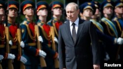 Russia's President Vladimir Putin, front, attends a ceremony to commemorate the anniversary of the beginning of the Great Patriotic War against Nazi Germany in 1941 near memorials by the Kremlin walls in Moscow, June 22, 2014. 