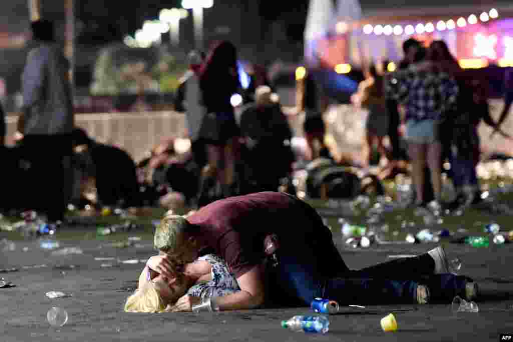 A man lays on top of a woman as others flee the Route 91 Harvest country music festival grounds after a active shooter was reported on October 1, 2017 in Las Vegas, Nevada.