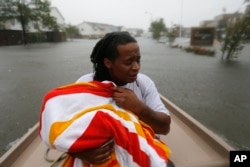 Demetres Fair holds a towel over his daughter Damouri Fair, 2, as they are rescued by boat by members of the Louisiana Department of Wildlife and Fisheries and the Houston Fire Department during flooding from Tropical Storm Harvey in Houston, Aug. 28, 2017.