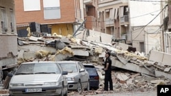 A police officer looks at the damage in Lorca, Spain a day after an earthquake hit the region, May 12, 2011.