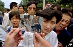 FILE- In this file photo take June 5, 1989, people on Chang'an Boulevard hold up a photo that they described as dead victims of the violence against pro-democracy protesters on Tiananmen Square, Beijing. Hundreds had been killed in the early morning hours