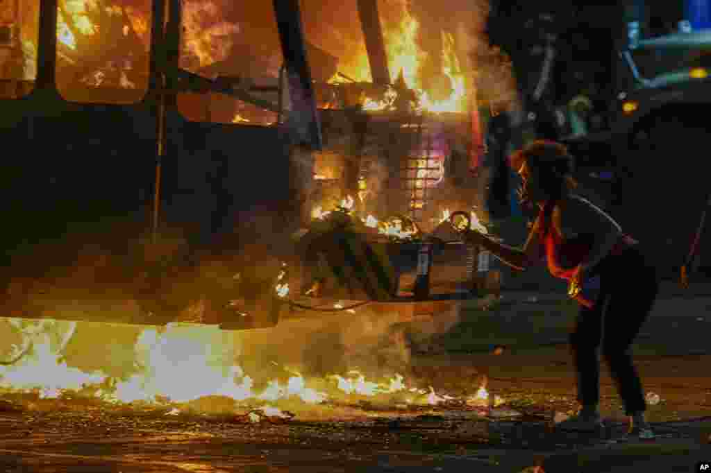 A protester lights a cigarette on a garbage truck that was set on fire during a demonstration Aug. 24, 2020, in Kenosha, Wis., sparked by the shooting of Jacob Blake by a Kenosha Police officer a day earlier.