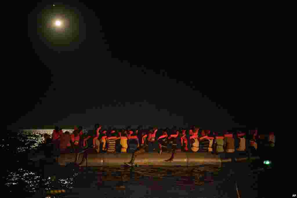 African migrants wait to be assisted by crew members of the Louise Michel and Astral rescue vessels, after being located sailing adrift on an overcrowded rubber boat, 70 miles southwest Malta, in the Central Mediterranean sea, Aug. 29, 2020.