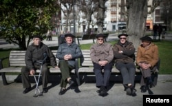 FILE - Retired men sit in the sunshine in the Spanish Basque fishing town of Bermeo, March 6, 2015. Spain's aging population and falling birth rate pose a threat to its future.