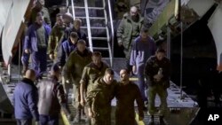 In this handout photo taken from video released by the Russian Defense Ministry Press Service Sept. 22, 2022, a group of Russian prisoners of war exit a Russian military plane after they were released by Ukraine, at an unspecified location in Russia. 