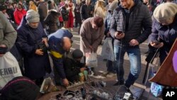 People charge their phones, try to connect to the internet and make phone calls on central square in Kherson, Ukraine, Nov. 15, 2022. Waves of Russian airstrikes rocked Ukraine on Tuesday, knocking out power throughout the country.