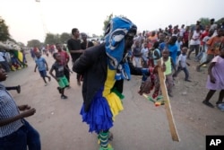 Gule Wamkulu baila miembros de la sociedad secreta con máscaras sangrientas y atuendos coloridos caminando por las calles camino a su actuación de danza ritual en Harare, Zimbabue, el 23 de octubre de 2022.