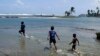 ARCHIVO- Niños juegan con botes de madera hechos en casa en la playa de Viento Frío, Panamá. 