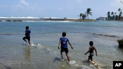 ARCHIVO- Niños juegan con botes de madera hechos en casa en la playa de Viento Frío, Panamá. 