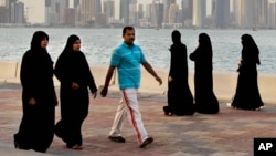 FILE- Qatari women and a man walk in front of the city skyline in Doha, Qatar, April 7, 2012. The foreign fans descending on Doha for the 2022 FIFA World Cup will find a country where women work, hold public office and cruise in their supercars along the city's palm-lined corniche.