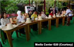 Ibu Iriana Jokowi bersama para pendamping KTT G20 mengikuti workshop menghias dengan teknik decoupage atau transfer media pada kerajinan berbahan dasar daun lontar yang telah dibentuk menjadi tas atau topi. (Foto: Courtesy/Media Center G20)