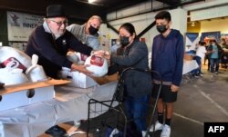 FILE - People receive their Thanksgiving Day turkey and sides in a giveaway to inner-city families on Nov. 22, 2021 in Los Angeles, California.