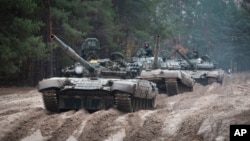 FILE - Ukrainian soldiers riding on captured Russian T-72 tanks conduct military training close to the Ukraine-Belarus border, near Chernihiv, Ukraine, Oct. 28, 2022. Navigating the terrain will soon be a challenge for Ukrainian and Russian troops as winter arrives.