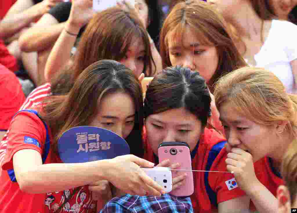 South Korean soccer fans use their smartphones to watch a live broadcast of the group H World Cup soccer match between Russia and South Korea, as the screen was turned off due to a network error at a public viewing venue in Seoul, South Korea.