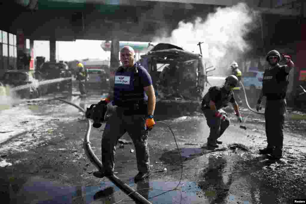 Israeli police explosive experts survey the scene at a gas station after it was hit by a rocket in the southern city of Ashdod, Israel, July 11, 2014.