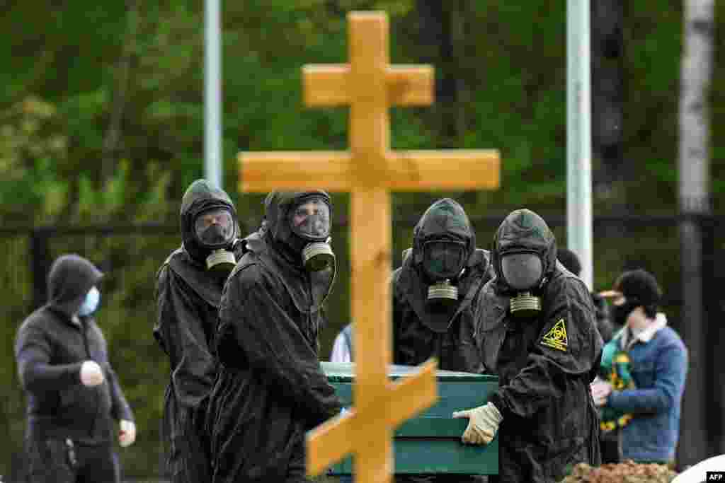 Cemetery workers wearing protective equipment bury a coronavirus victim at a cemetery in the outer part of Moscow, Russia.