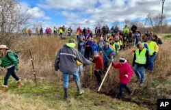 FILE - In this Oct. 23, 2018, file photo, volunteers cross a creek and barbed wire near Barron, Wis., on their way to a ground search for 13-year-old Jayme Closs who was discovered missing Oct. 15 after her parents were found fatally shot at their home.