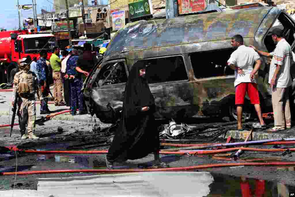 People and security forces inspect the site of a car bomb explosion in Basra, southeast of Baghdad, July 29, 2013. 