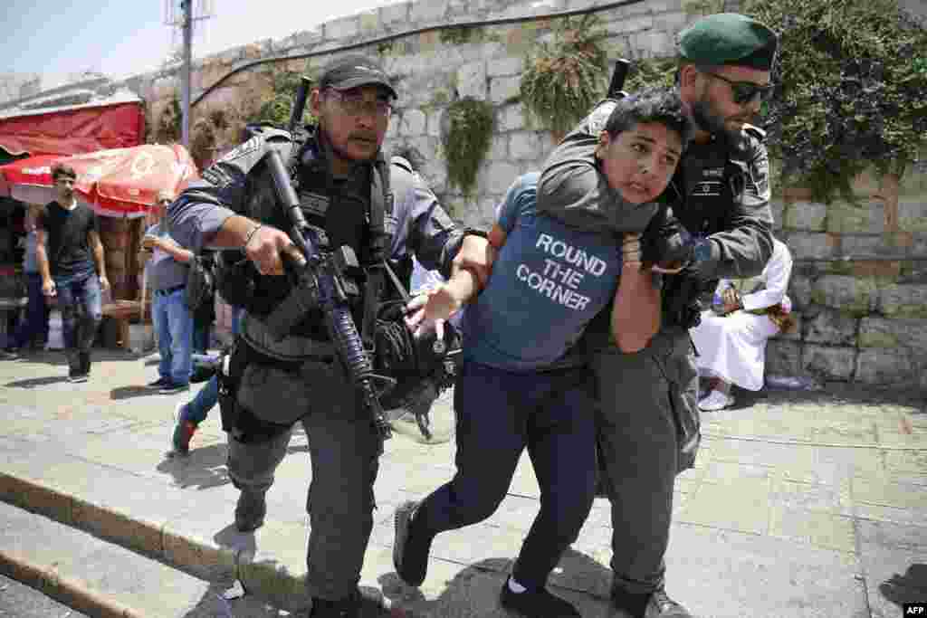Dua tentara penjaga perbatasan Israel menahan seorang remaja Palestina pada aksi demonstrasi di luar &#39;Pintu Gerbang Domba&#39; di kota kuno Yerusalem.