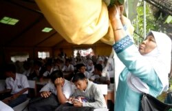 Seorang guru menggulung sebagian tenda UNICEF sebagai siswa belajar di sekolah mereka setelah dibuka kembali untuk kelas setelah gempa bumi Padang, Sumatera Barat, 5 Oktober 2009. (Foto: Reuters/Dadang Tri)