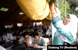 Seorang guru menggulung sebagian tenda UNICEF sebagai siswa belajar di sekolah mereka setelah dibuka kembali untuk kelas setelah gempa bumi Padang, Sumatera Barat, 5 Oktober 2009. (Foto: Reuters/Dadang Tri)