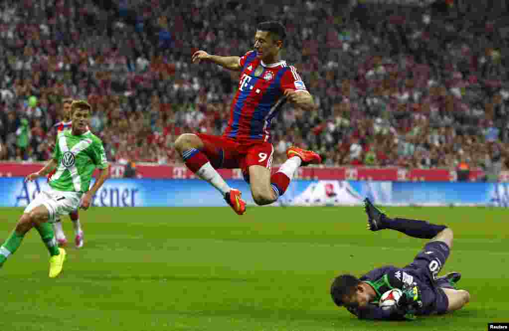 Bayern Munich's Robert Lewandowski jumps over VfL Wolfsburg's goalkeeper Max Gruen during their German Bundesliga first division soccer match in Munich August 22, 2014. REUTERS/Michaela Rehle (GERMANY - Tags: SPORT SOCCER TPX IMAGES OF THE DAY) DFL RULES 