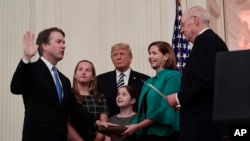 Retired Justice Anthony Kennedy, right, ceremonially swears-in Supreme Court Justice Brett Kavanaugh, as President Donald Trump looks on, in the East Room of the White House in Washington, Oct. 8, 2018. Ashley Kavanaugh holds the Bible and daughters Marga