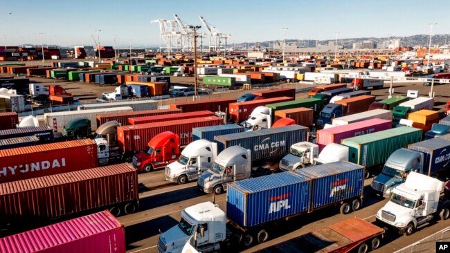 FILE - Trucks line up to enter a Port of Oakland shipping terminal, Nov. 10, 2021, in Oakland, Calif. The federal government is moving forward with a plan to let teenagers drive big rigs from state to state in a test program.