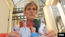 Brenda Caplen holds a photo of her son, Stuart (far left in photograph), who was killed in a collision in which alcohol was a deemed major causal factor. (D. Taylor/VOA)