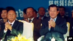 Cambodian Prime Minister Hun Sen, front right, applauds together with the National Assembly President Heng Samrin, front left, during an event by the ruling Cambodian People's Party marking the 36th anniversary of the 1979 downfall of the Khmer Rouge regi