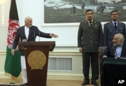 Afghan President Ashraf Ghani, left, points to Afghanistan's acting Defense Minister Masoom Stanikzai, sitting, during a press conference at the presidential palace in Kabul, Afghanistan, Sept. 29, 2015.