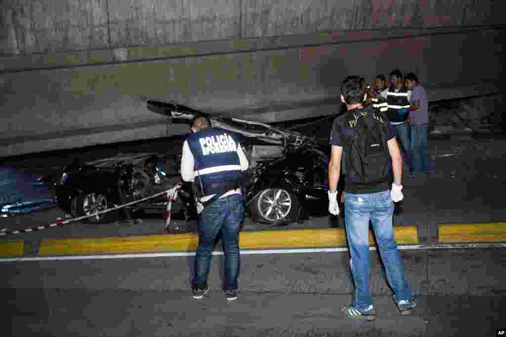 Police look at a car crushed under a collapsed overpass in Guayaquil, Ecuador, April 16, 2016.