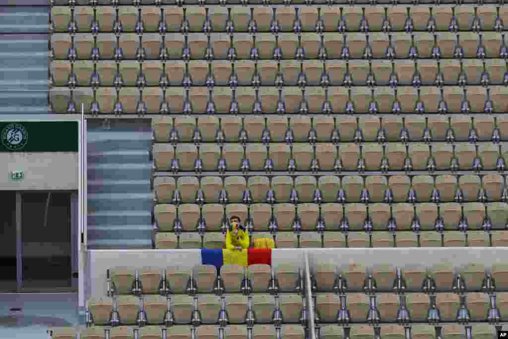 A lone fan with the Romanian flag and a face mask in the colors of the flag watches Romania&#39;s Simona Halep and Romania&#39;s Irina-Camelia Begu&#39;s second round match of the French Open tennis tournament in Suzanne Lenglen court at the Roland Garros stadium in Paris, France, Wednesday, Sept. 30, 2020. (AP Photo/Alessandra Tarantino)