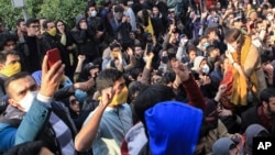 In this Saturday, Dec. 30, 2017 file photo taken by an individual not employed by the Associated Press and obtained by the AP outside Iran, university students attend a protest inside Tehran University while anti-riot Iranian police prevent them to join o