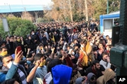 In this Saturday, Dec. 30, 2017 file photo taken by an individual not employed by the Associated Press and obtained by the AP outside Iran, university students attend a protest inside Tehran University while Iranian riot police prevent them to join others.