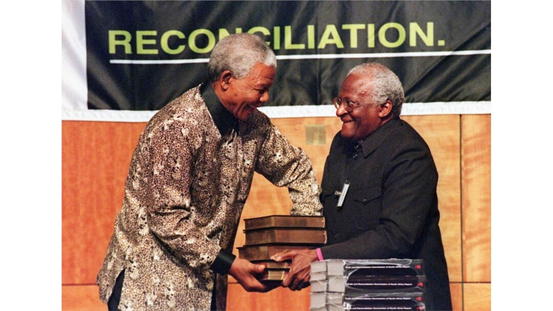 In this file photo taken on Oct. 29, 1998 South African President Nelson Mandela (L) receives a five volumes of Truth and Reconciliation Commission final report from Archbishop Desmond Tutu (R) in Pretoria.
