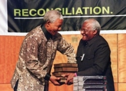 In this file photo taken on Oct. 29, 1998 South African President Nelson Mandela (L) receives a five volumes of Truth and Reconciliation Commission final report from Archbishop Desmond Tutu (R) in Pretoria.